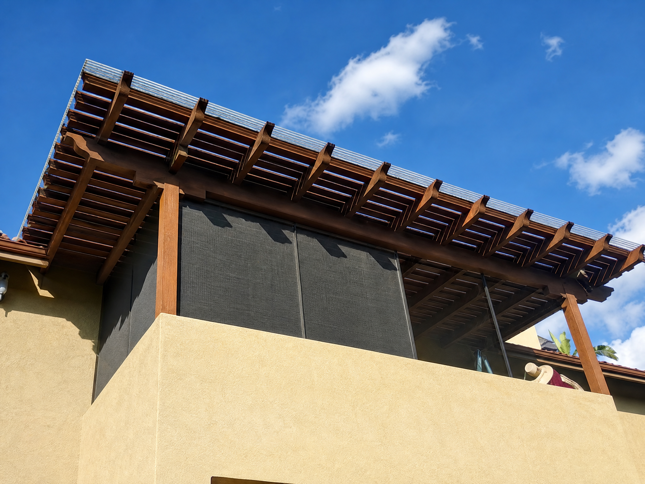 Modern house balcony with wooden pergola overhang and dark screened enclosure panels