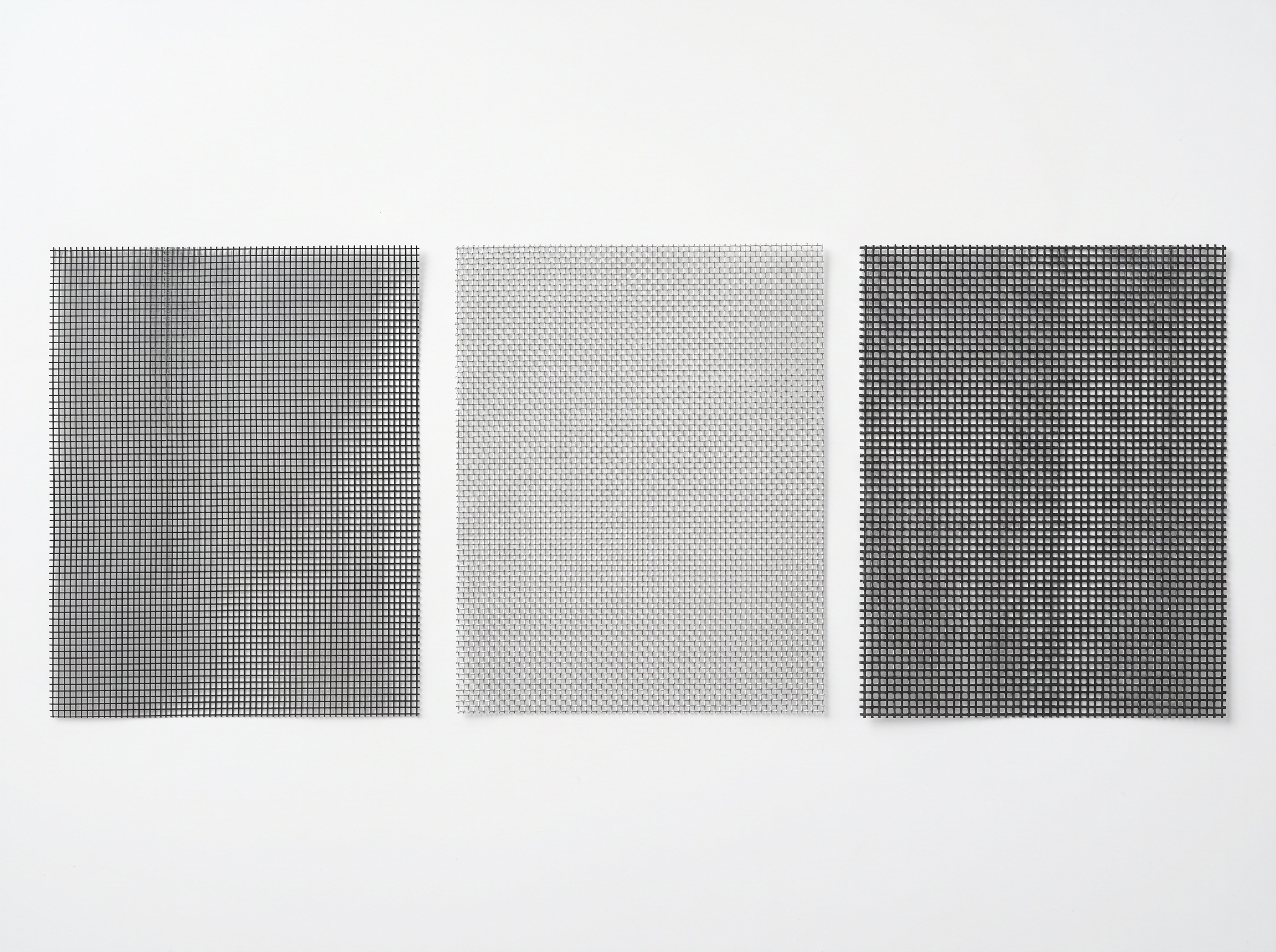 Three window screen mesh samples side by side: standard charcoal fiberglass, silver aluminum, and dark pet-resistant polyester mesh