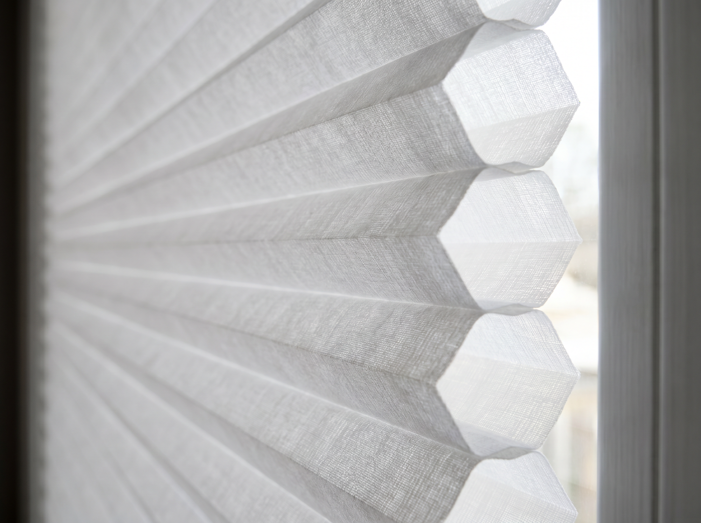 Close-up side view of honeycomb cellular window shade showing the distinctive air pocket cells that provide insulation