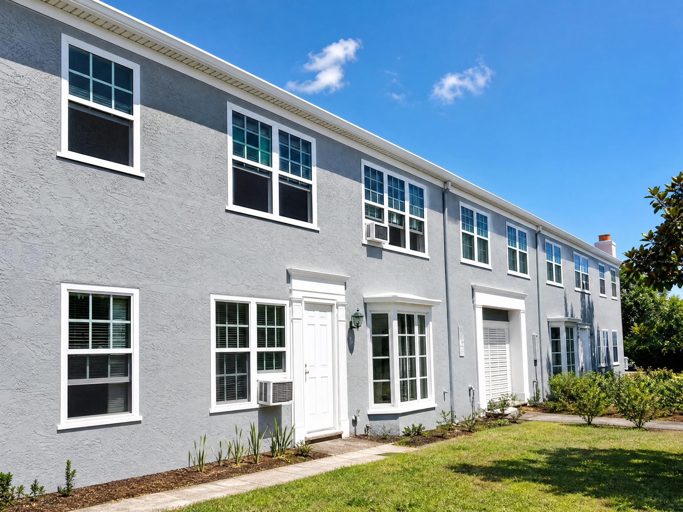 Gray two-story apartment building with white-trim windows and door screens