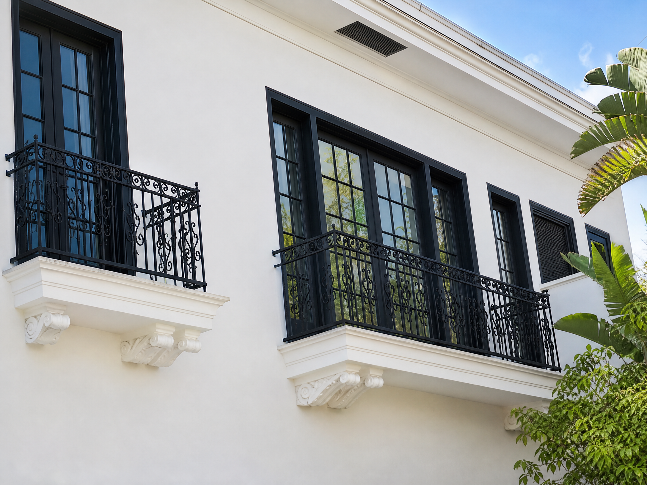 White building facade with black wrought-iron balcony railings and window screens installed by Screen Masters
