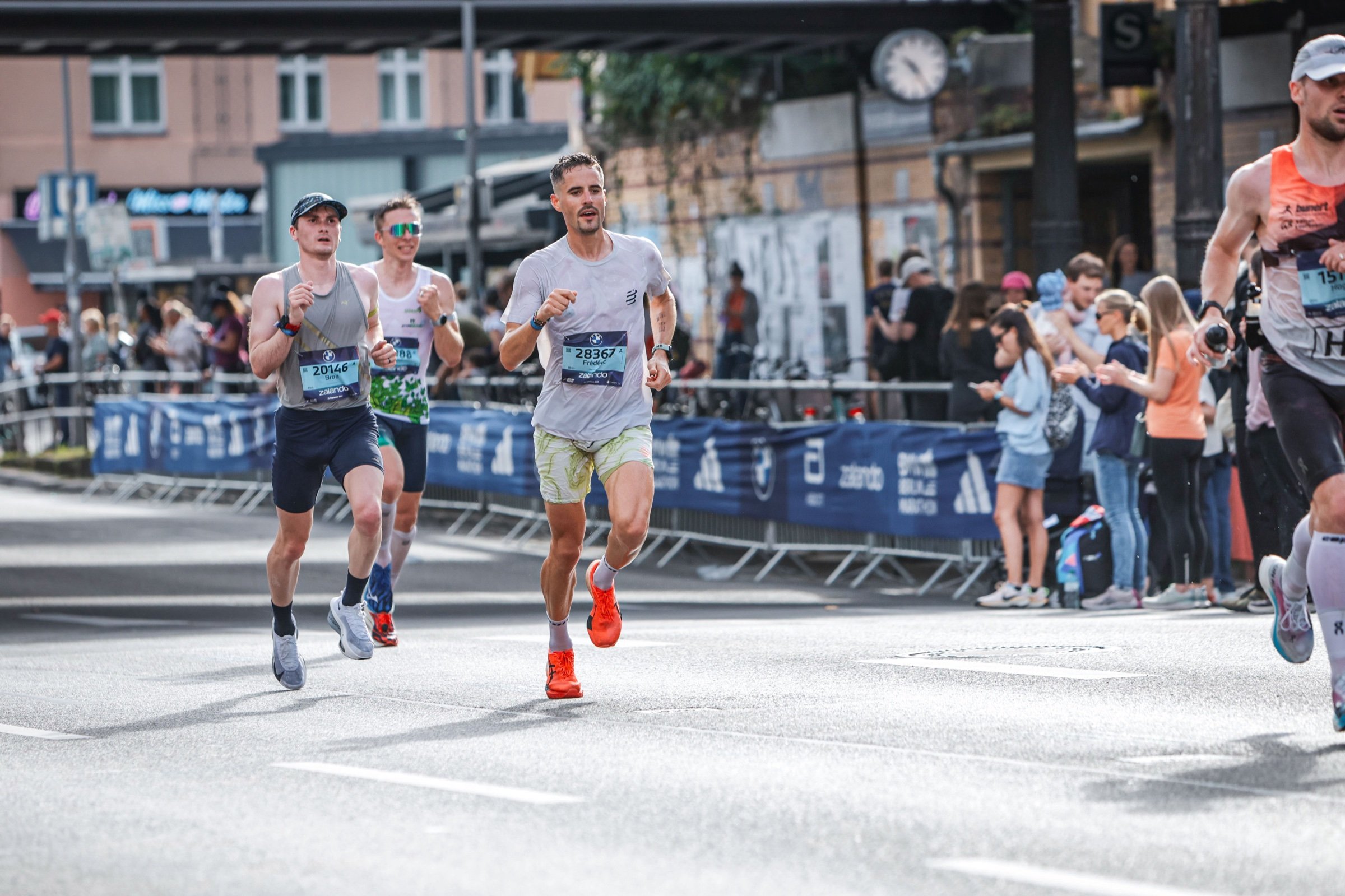 Frédéric running a city marathon among other runners, with spectators behind barriers.