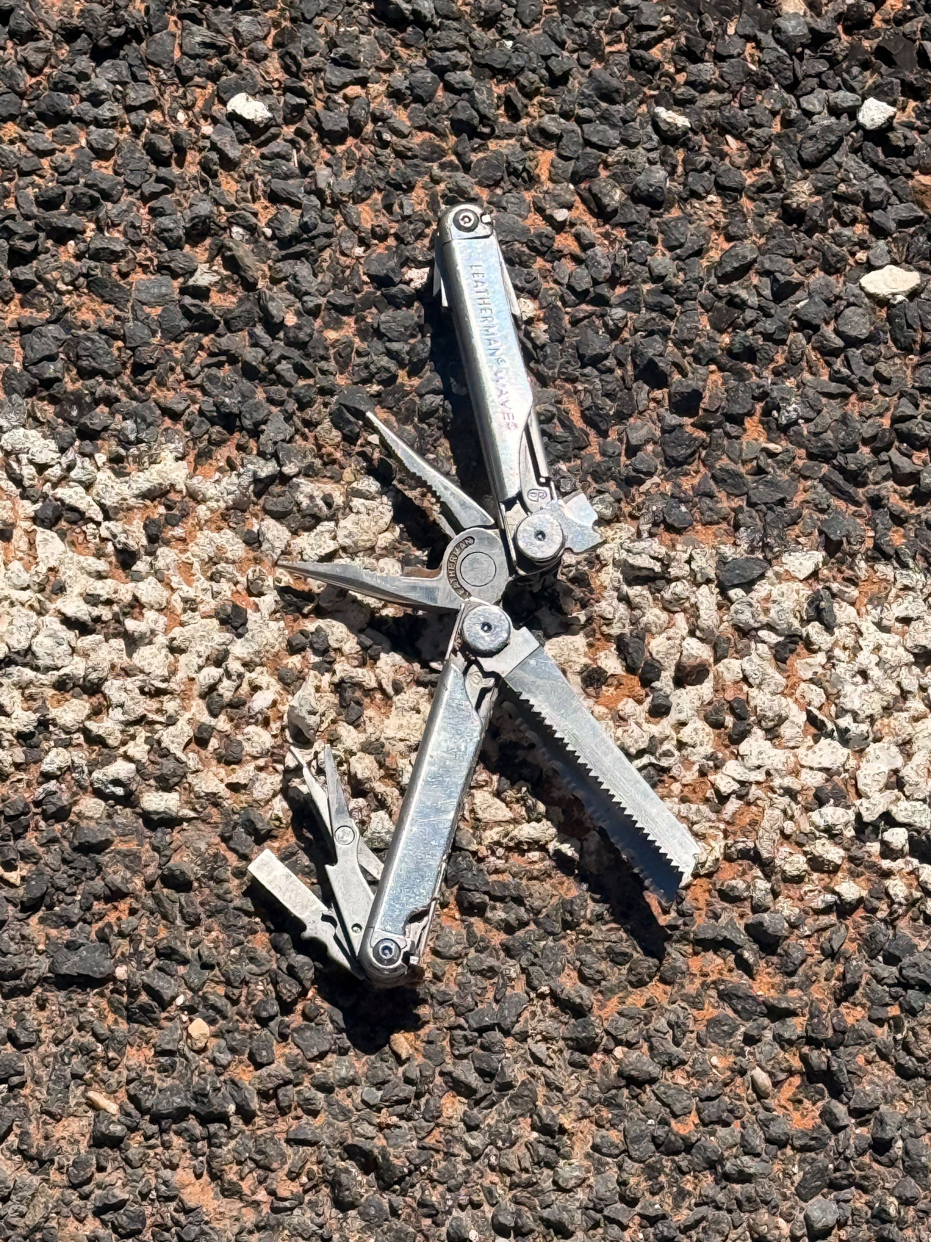 A multitool lying open on volcanic gravel