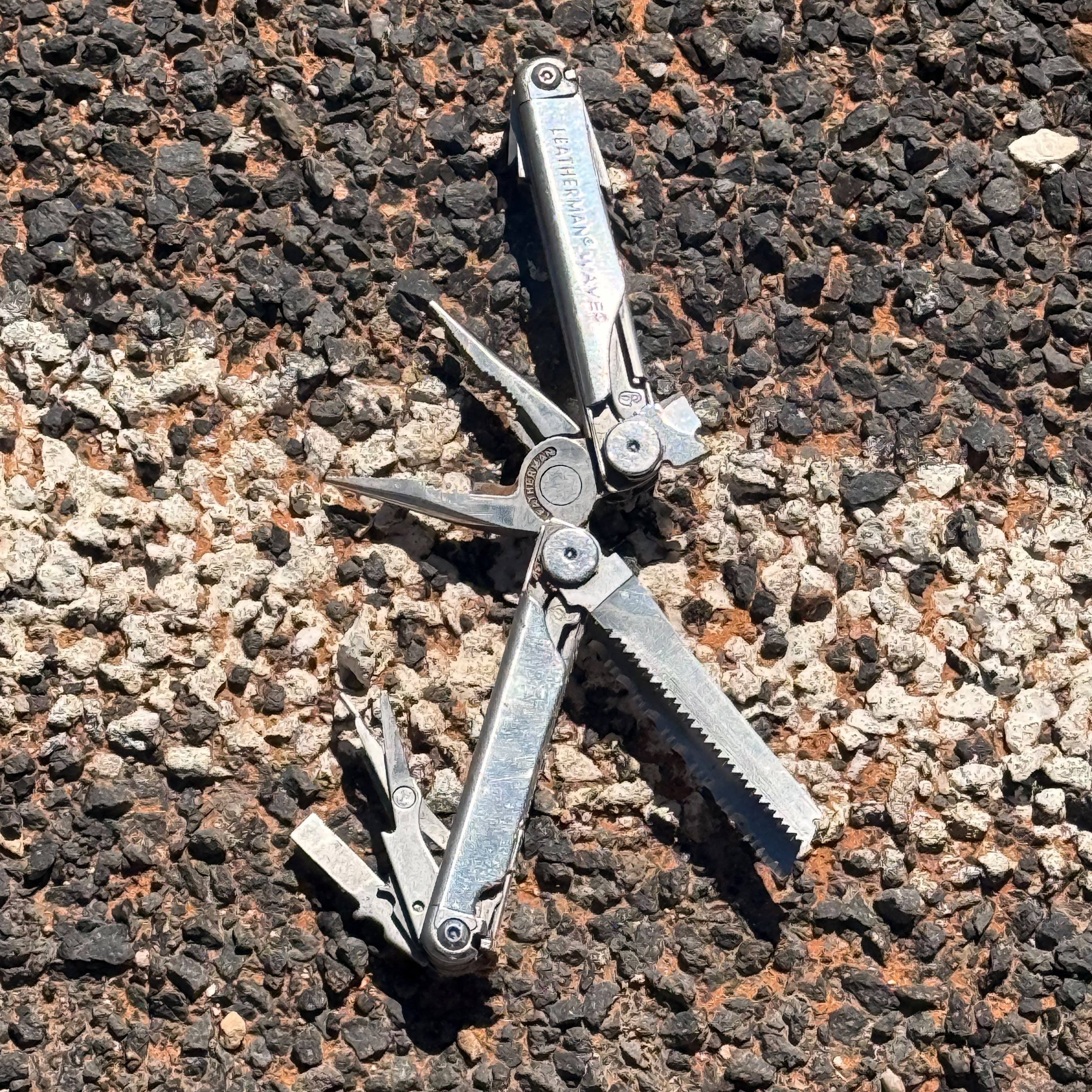 A multitool lying open on volcanic gravel