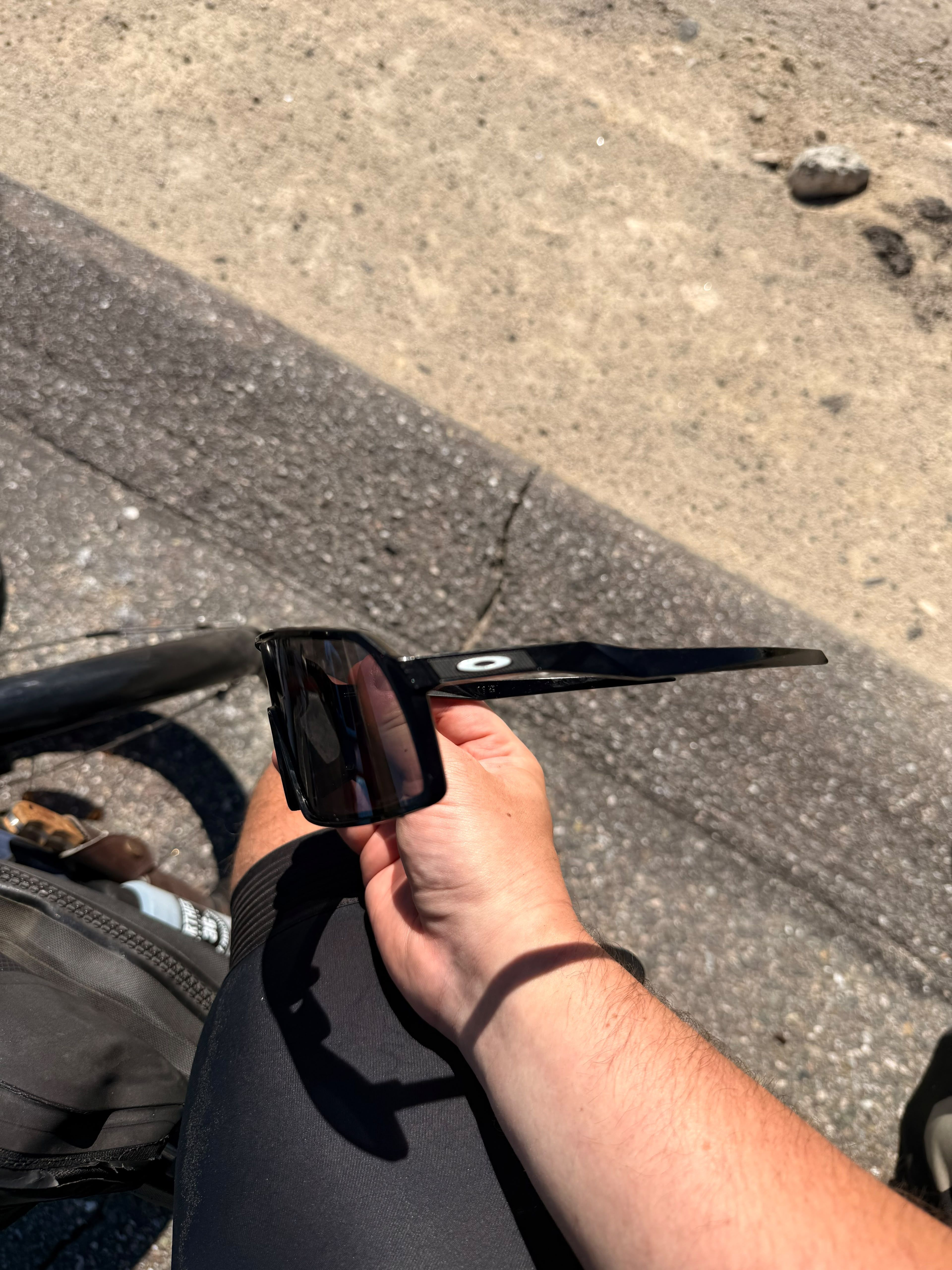 Oakley sunglasses held in a hand above the handlebars