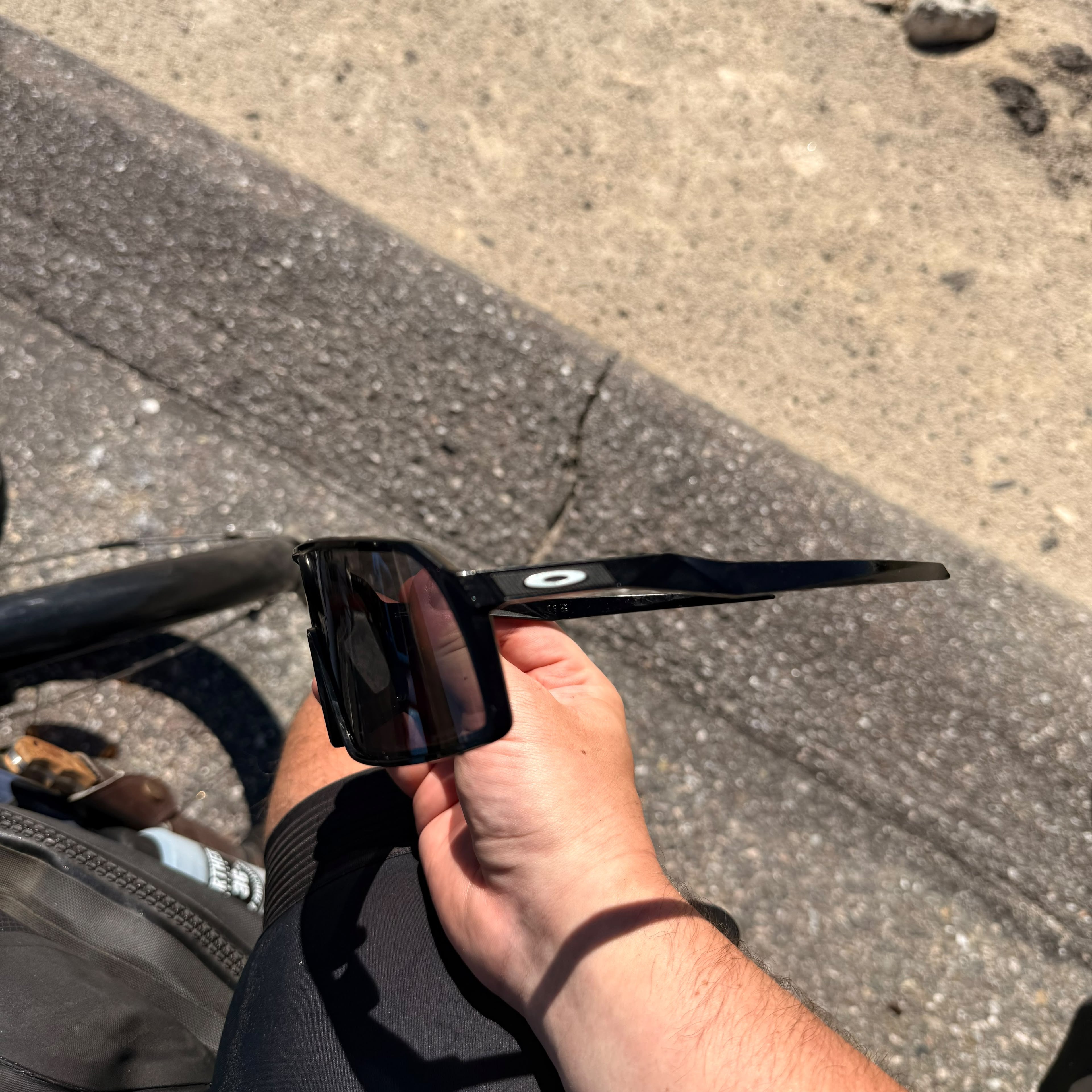 Oakley sunglasses held in a hand above the handlebars