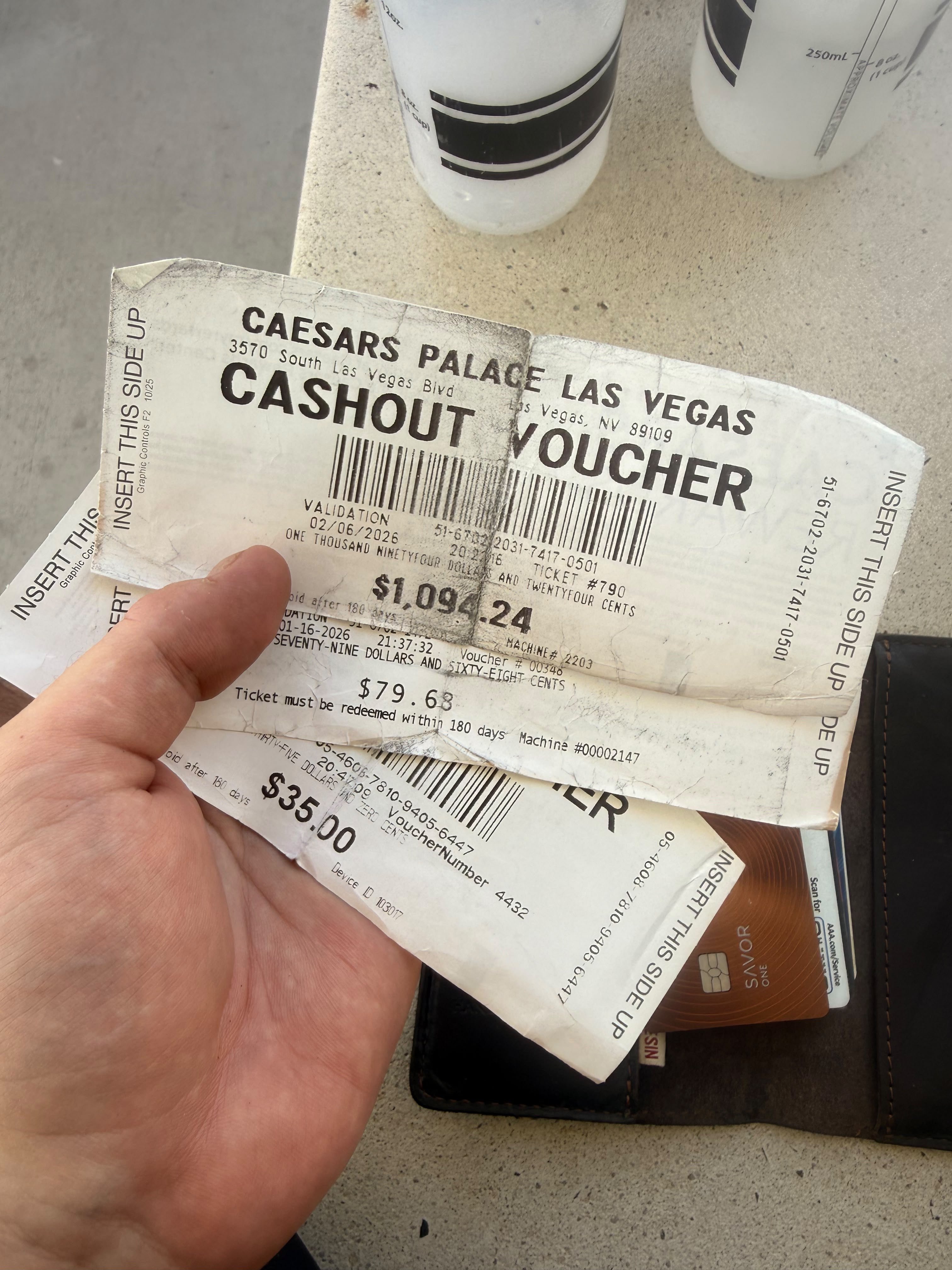Three Caesars Palace cashout vouchers held in a hand, the top one for $1,094.24