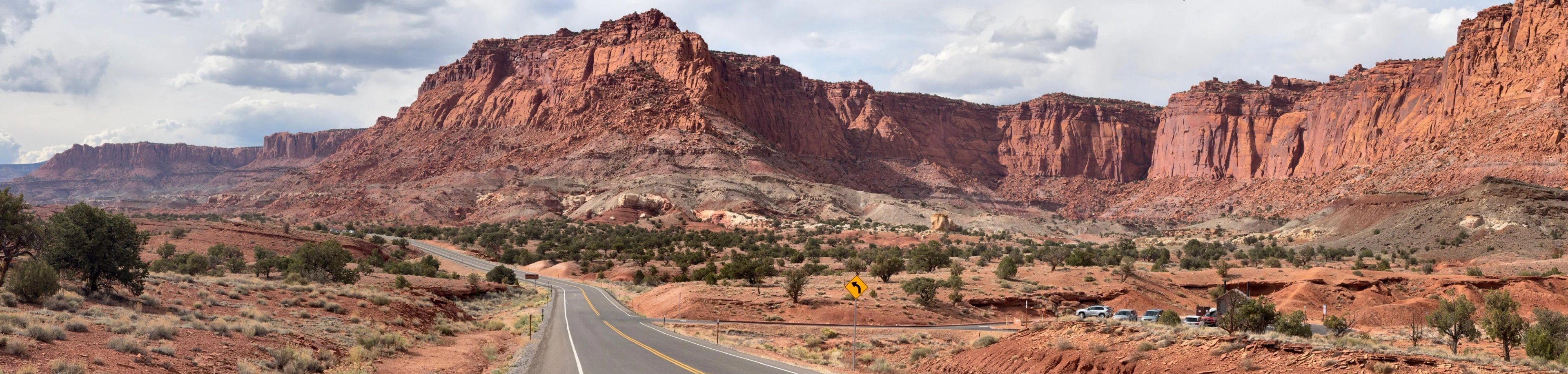 Red rock cliffs above an empty two lane road in the American desert