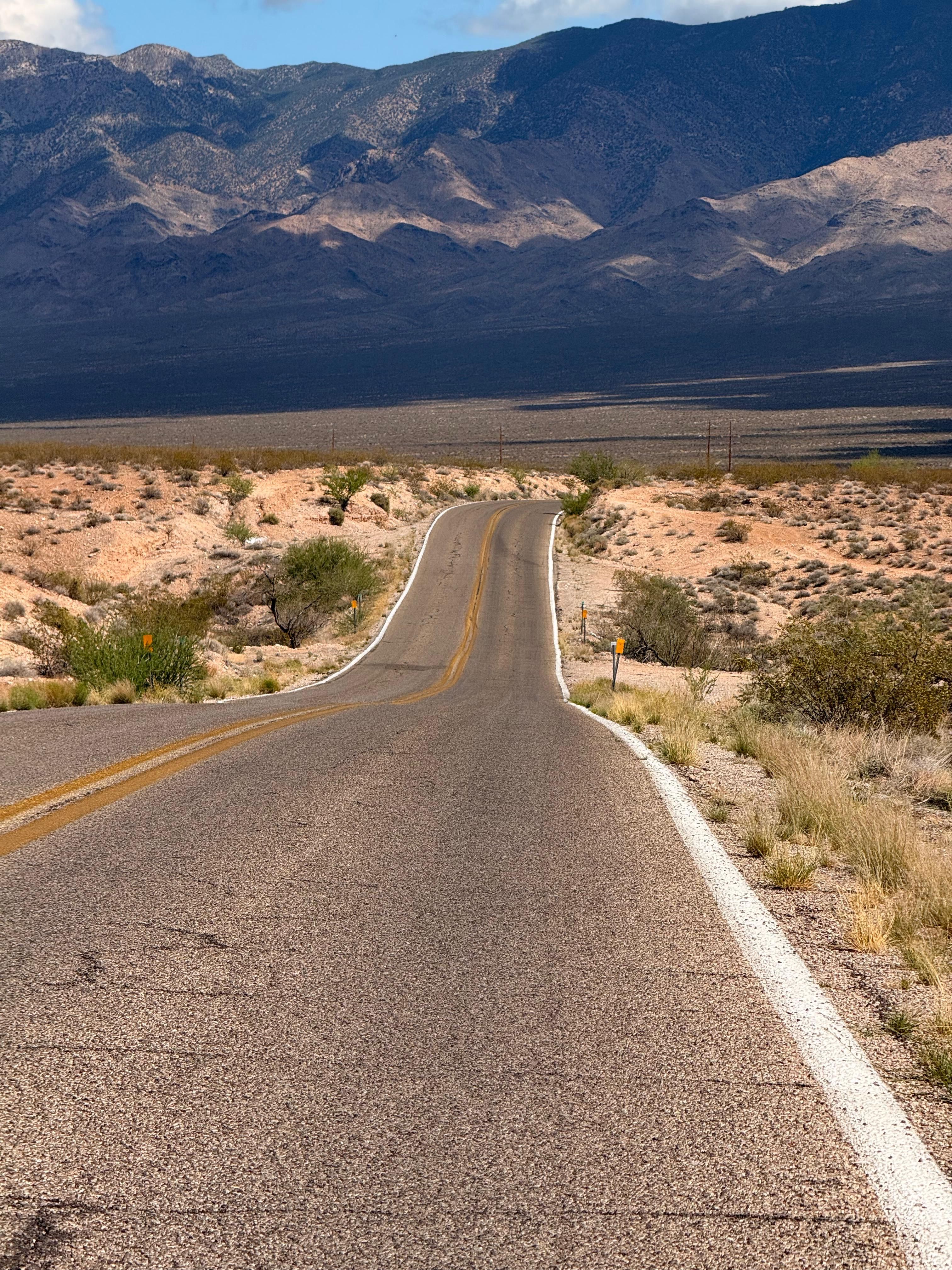 An empty desert road running toward mountains