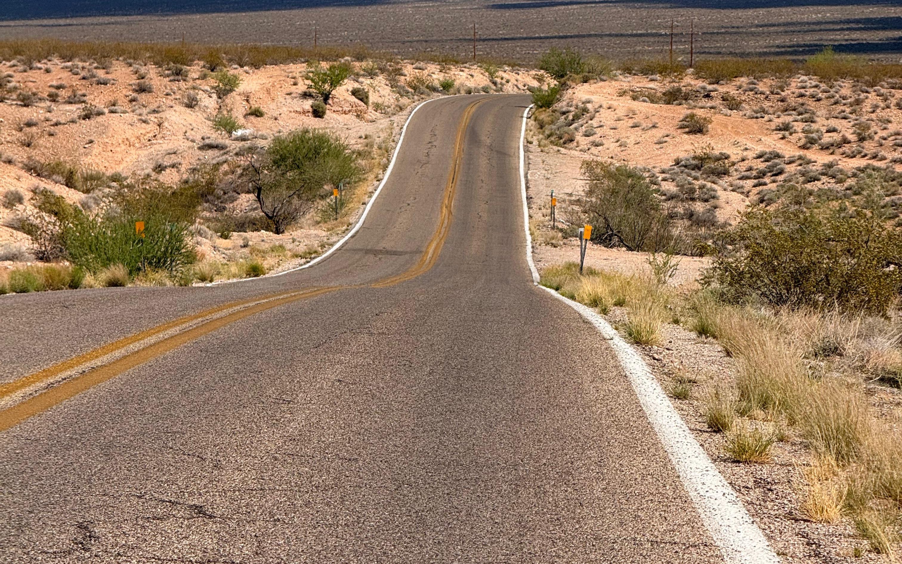An empty desert road running toward mountains