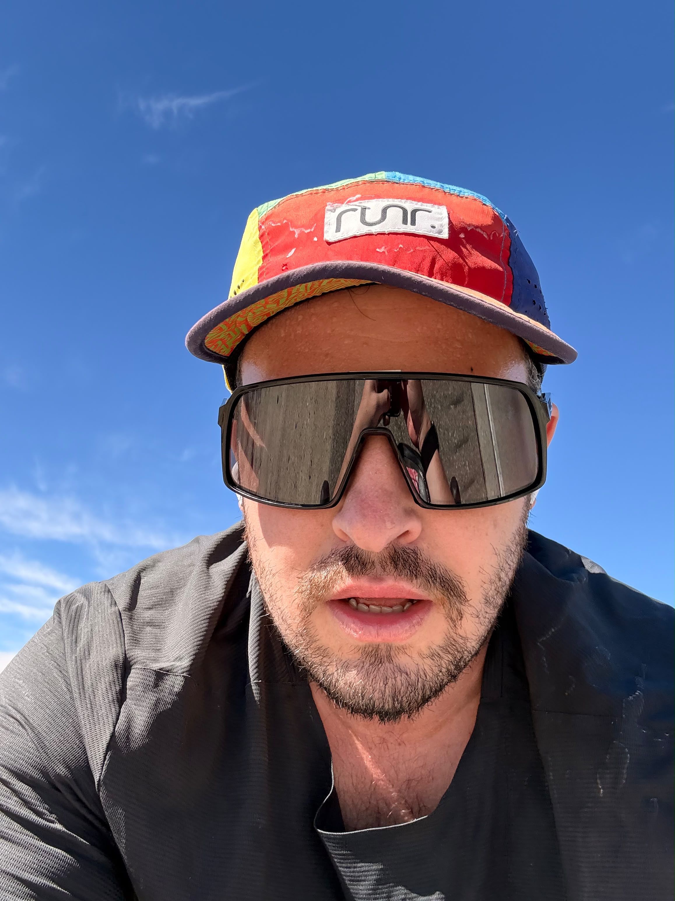 Ben Clark in a cycling cap and sunglasses under a blue sky