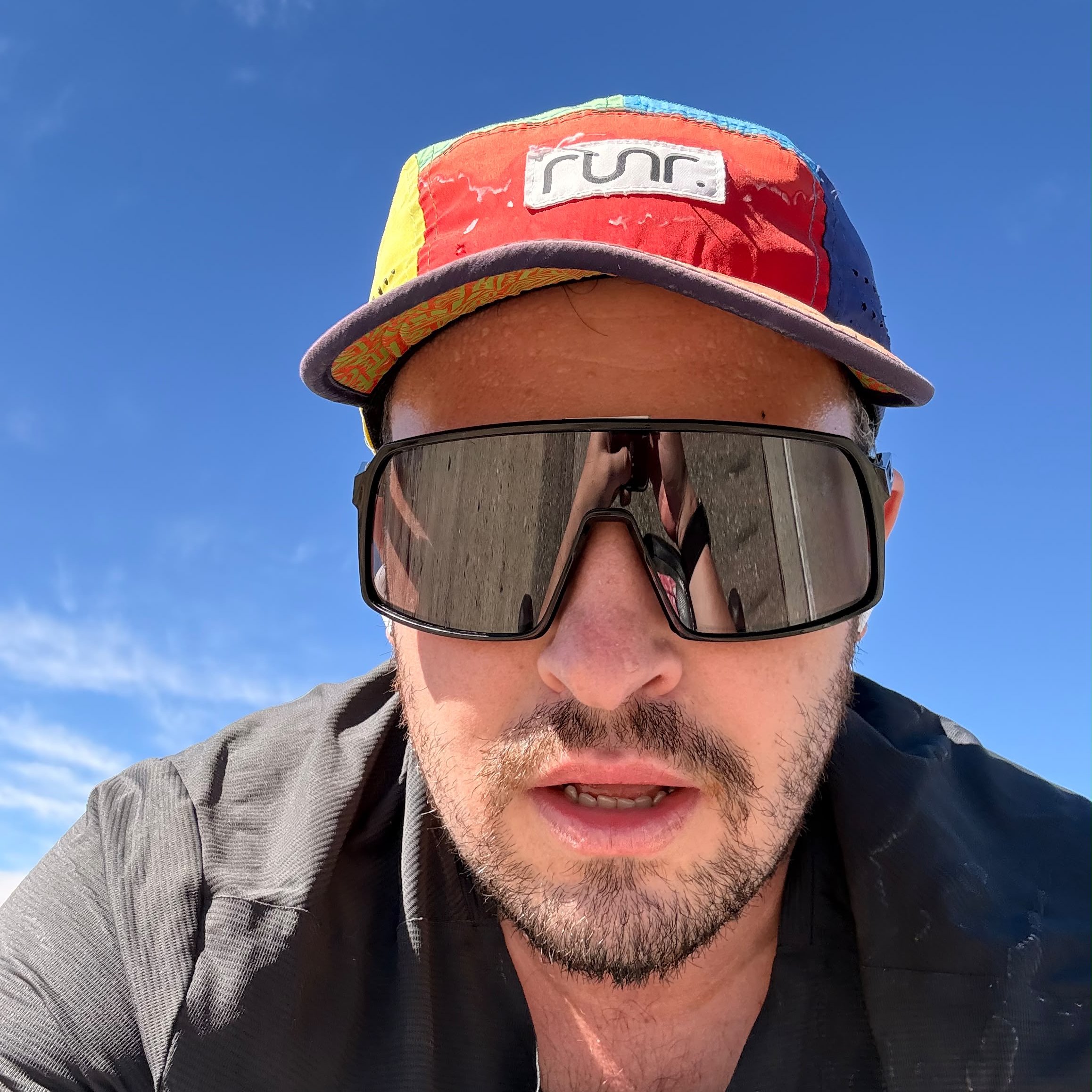 Ben Clark in a cycling cap and sunglasses under a blue sky