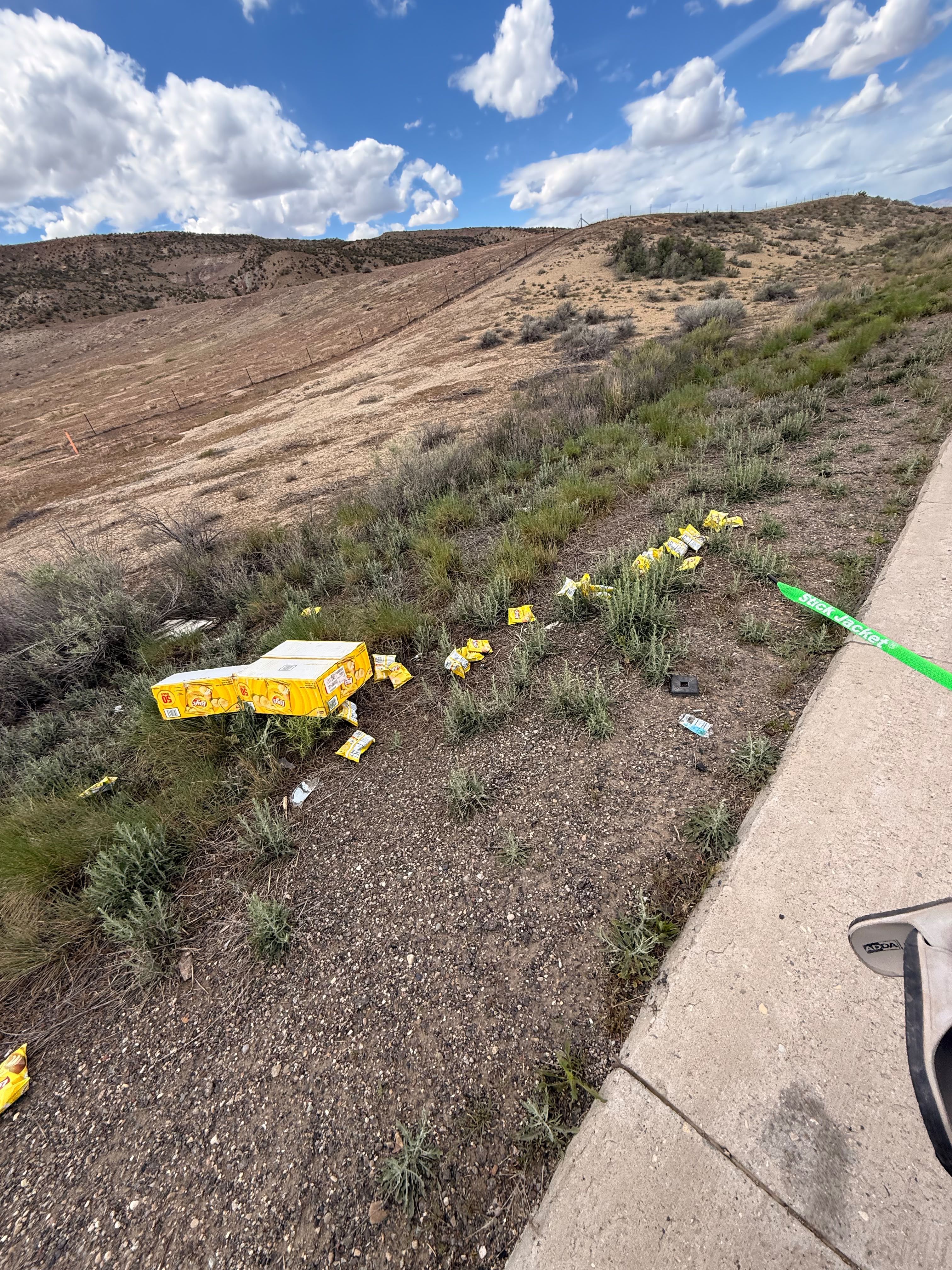 Boxes of crisps scattered up a hillside beside the road