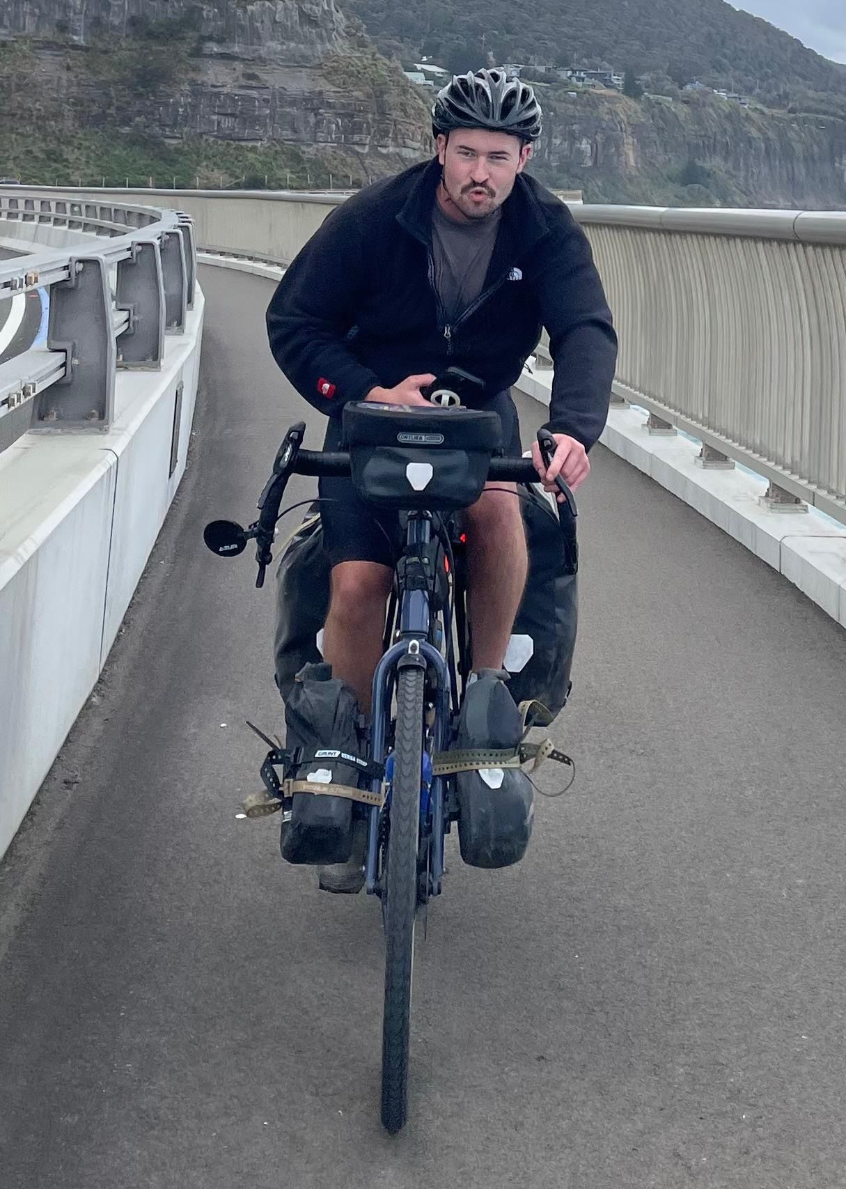 A loaded touring bicycle ridden across a coastal bridge