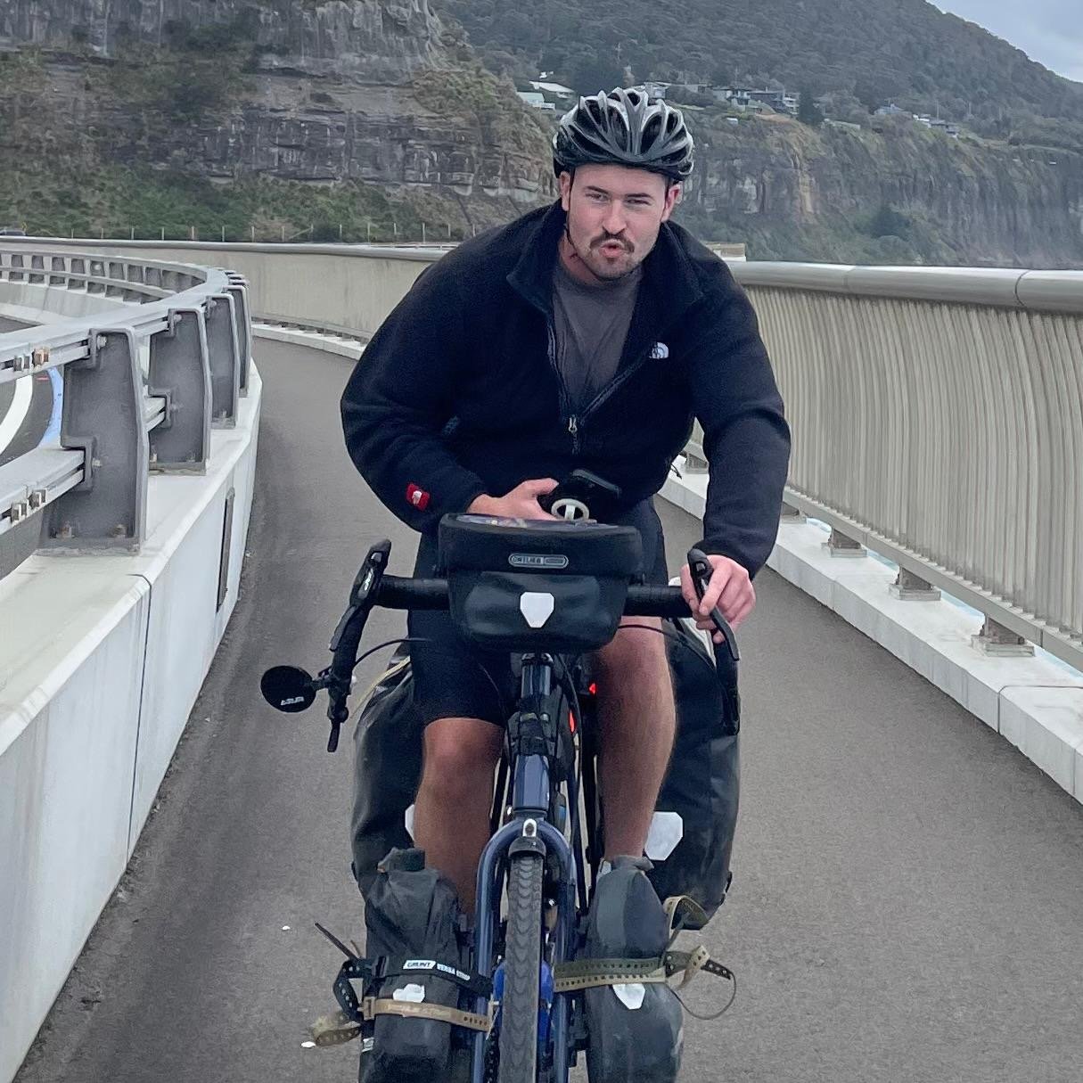 A loaded touring bicycle ridden across a coastal bridge