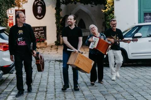 Die Band geht eine Gasse entlang, eine Person trägt das Cajón, eine spielt Akkordeon