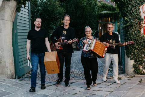 Ka Lerchal zu viert auf einer Pflastergasse, mit Cajón, Gitarren und Akkordeon