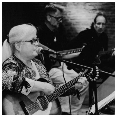 Schwarz-Weiß-Foto der Sängerin mit Gitarre am Mikrofon