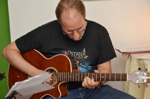 Gitarrist beim Spielen, konzentriert über die Noten gebeugt