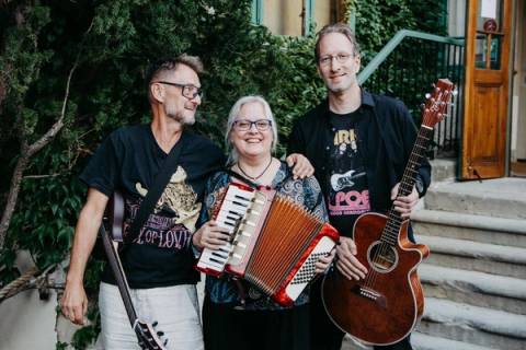 Porträt von drei Bandmitgliedern mit Akkordeon und Gitarre vor Stufen