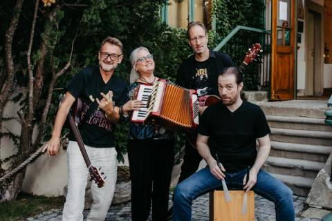 Die Band lachend vor einer Holztür, vorne sitzt der Cajón-Spieler