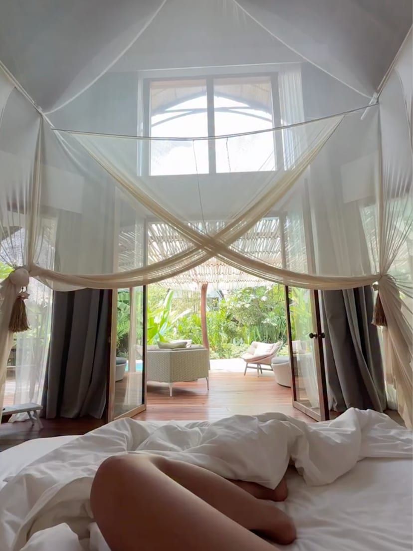 The bedroom of a villa at Nay Palad Hideaway, with the bed under a mosquito net and the garden beyond