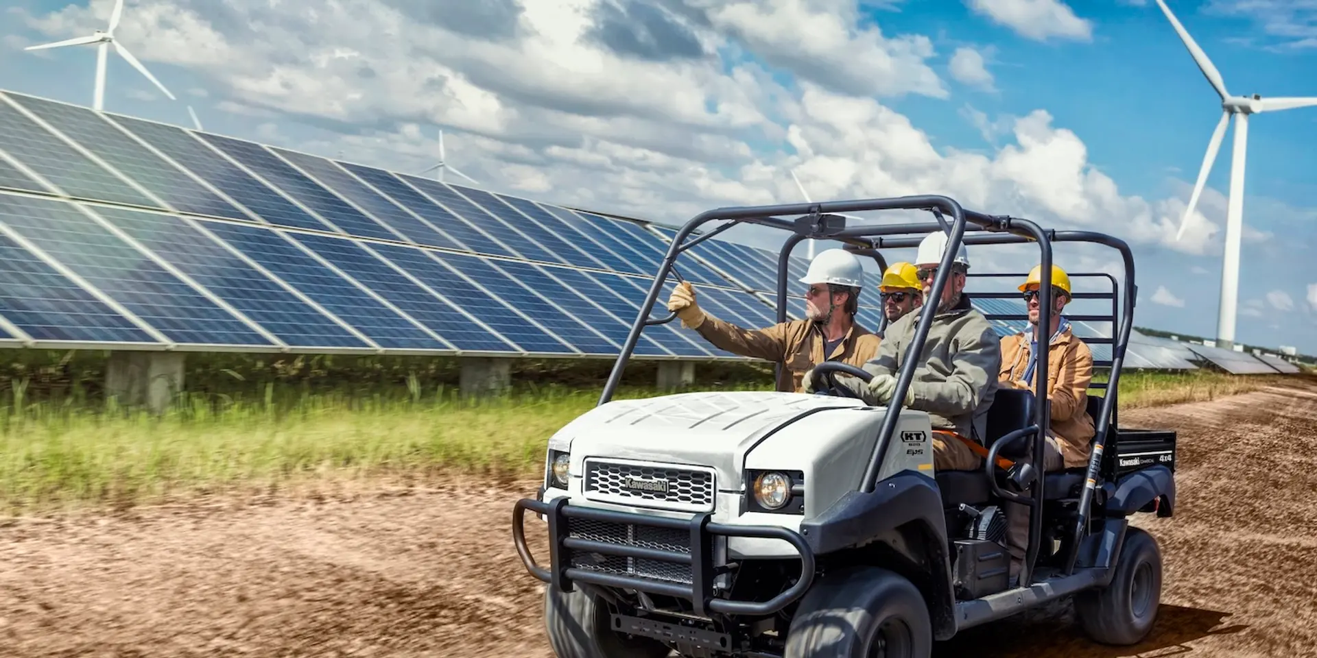 A white Kawasaki UTV driving past solar panels.