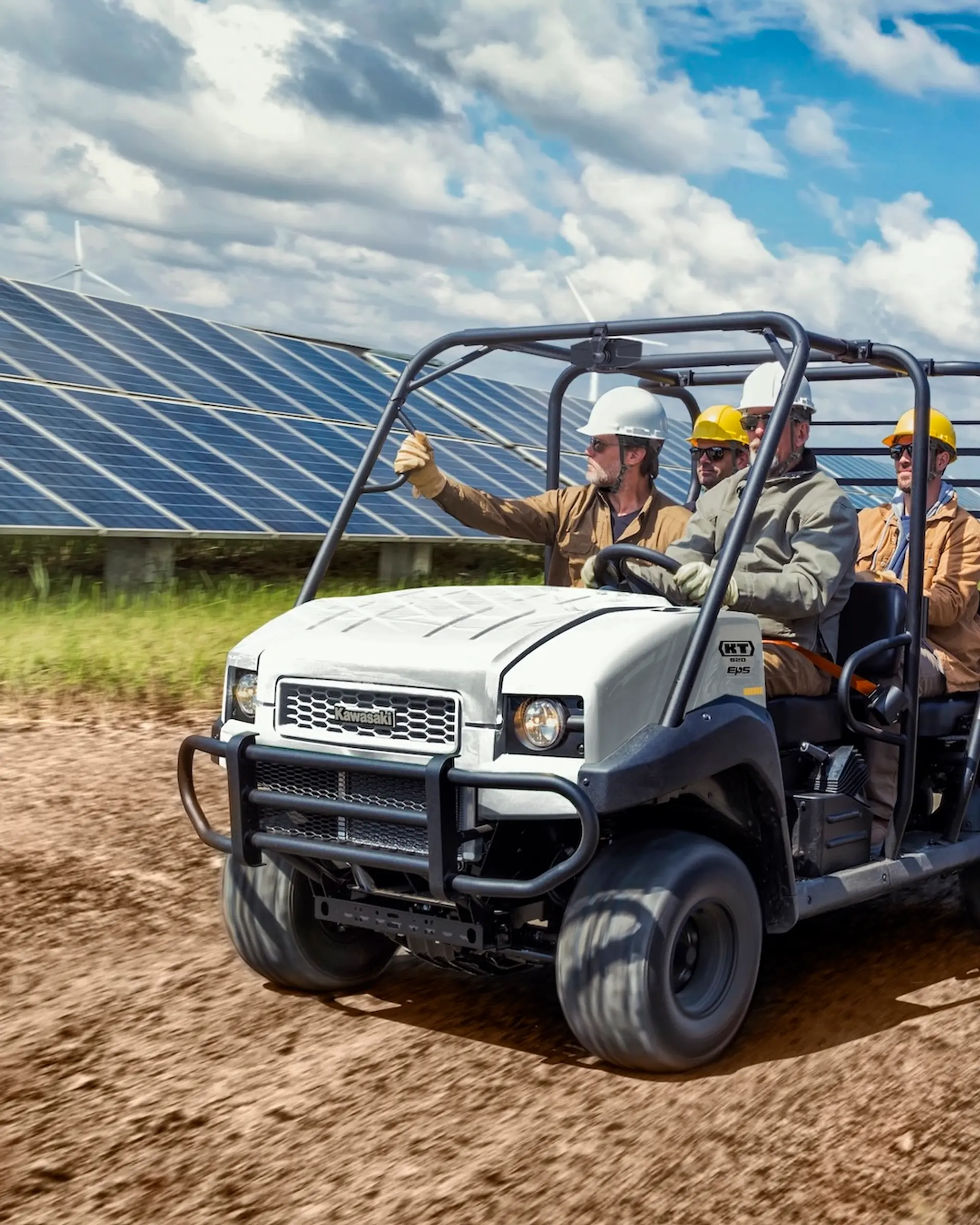 A white Kawasaki UTV driving past solar panels.