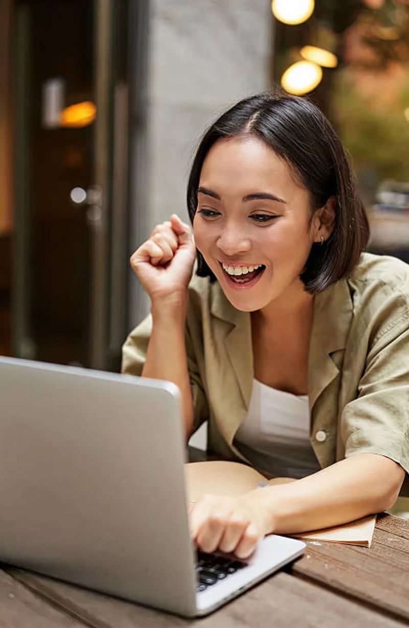 Young woman with laptop smiling excitedly