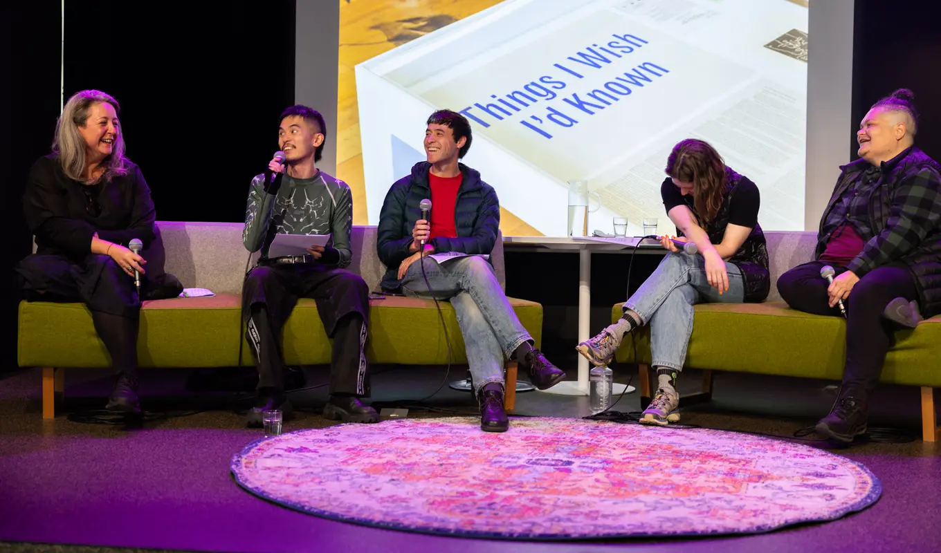 Panel discussion of 5 individuals. Frontal image of all of them. 4 out of 5 of them are looking at Lisa Radford, laughing. The other has their head tilted downward with their arms crossed.
