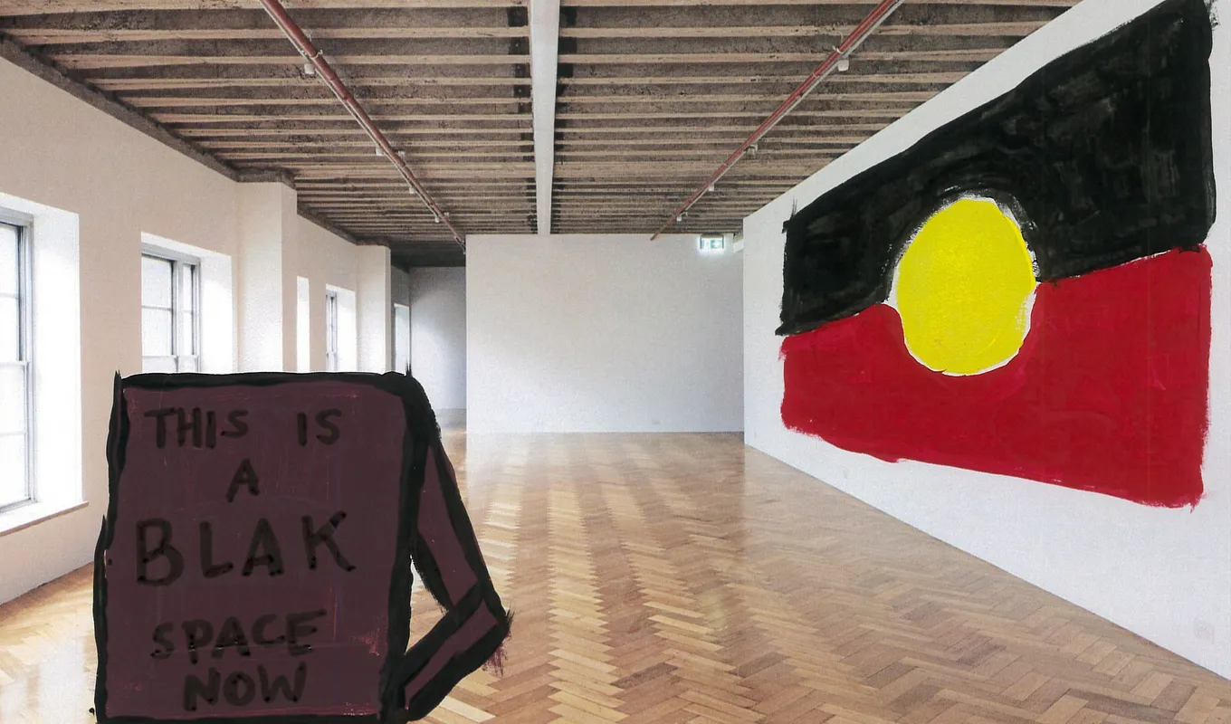 A photo of West Space's white walled gallery that has been painted over with the Aboriginal flag on the wall and a sign on the floor that reads "THIS IS A BLACK SPACE NOW".