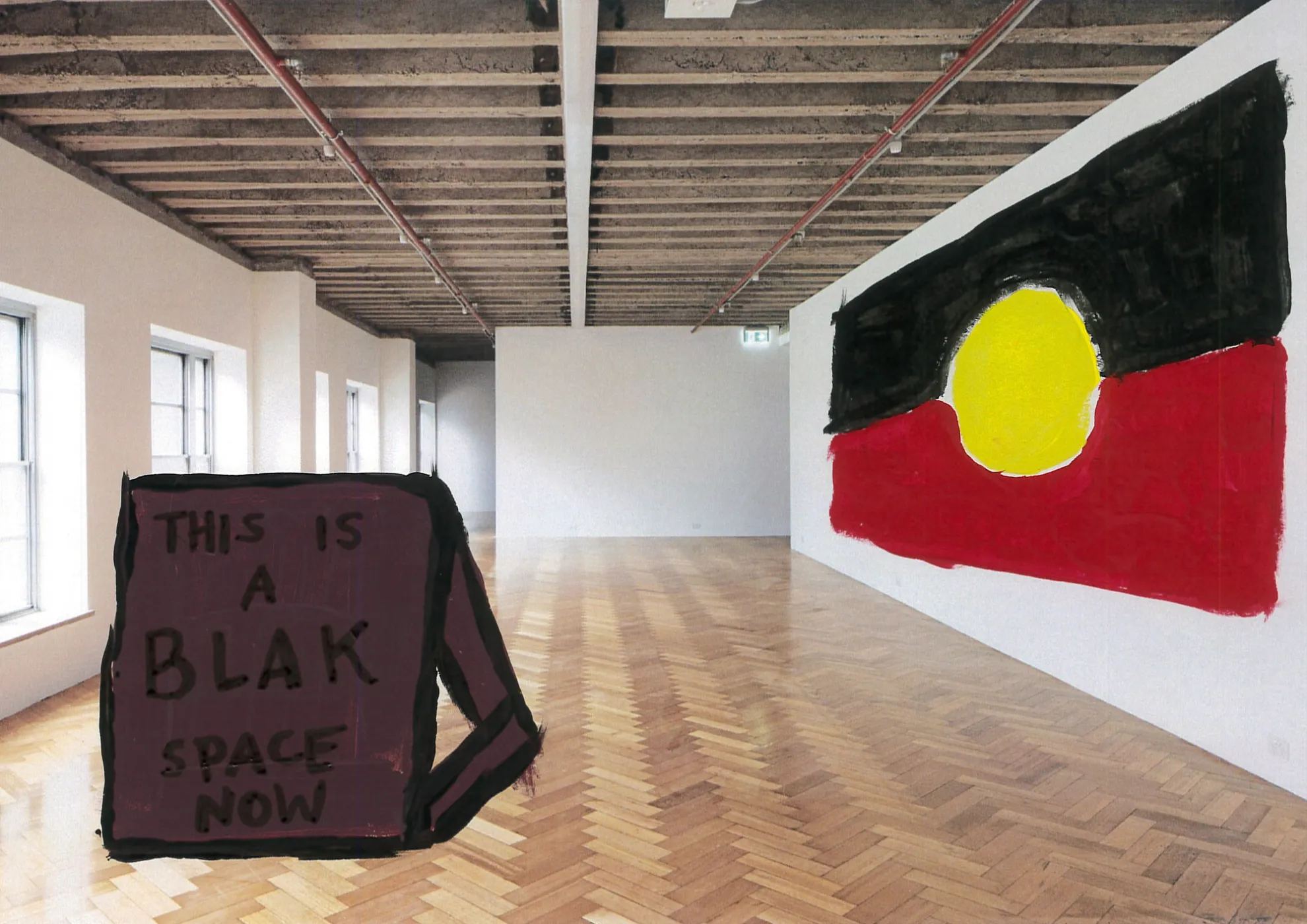 A photo of West Space's white walled gallery that has been painted over with the Aboriginal flag on the wall and a sign on the floor that reads "THIS IS A BLACK SPACE NOW".