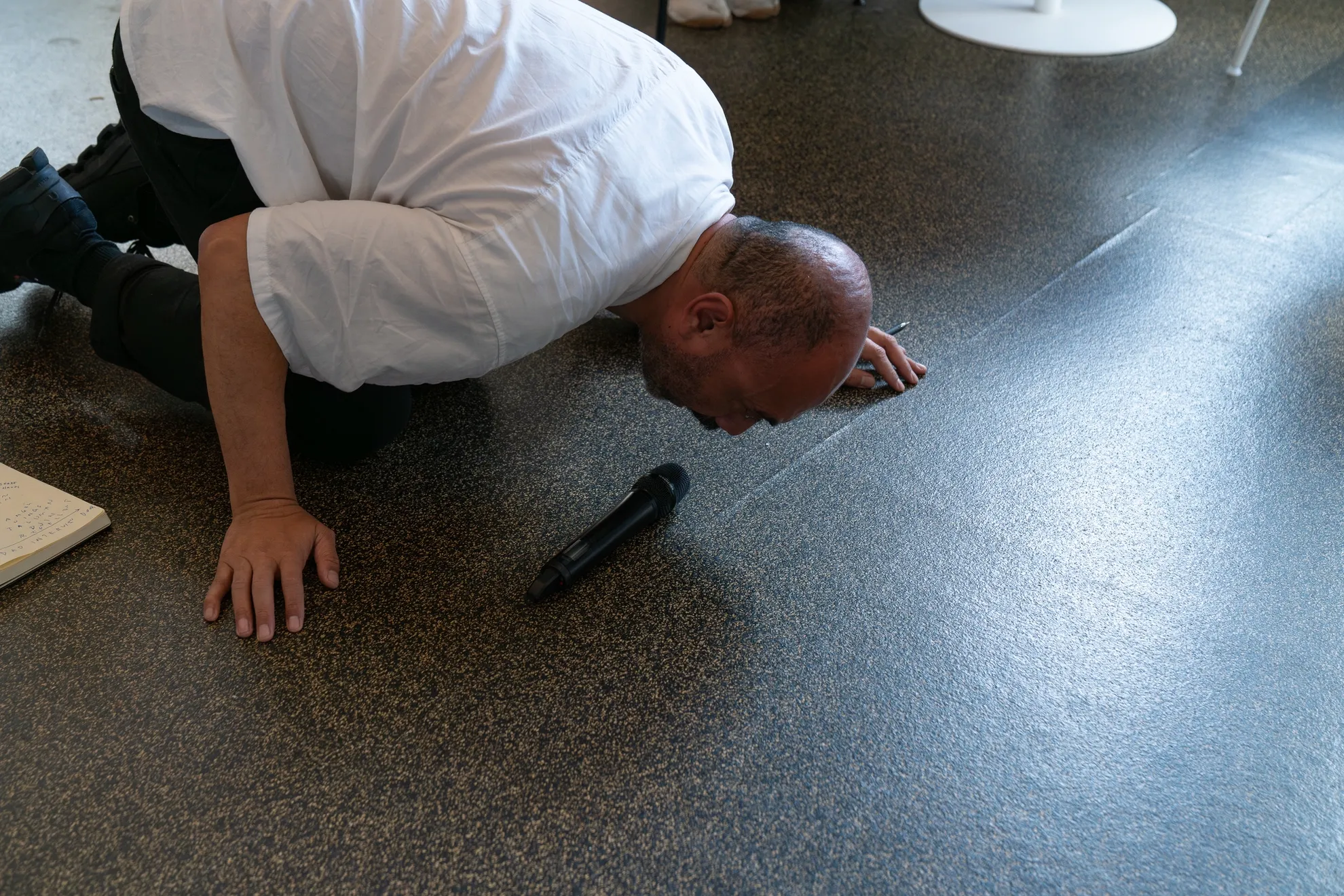 Brian leans to meet a microphone on the floor on all fours