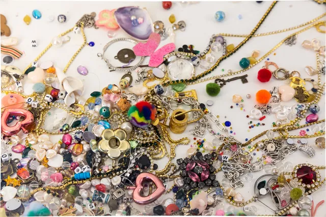A detail from Matilda Davis' installation "I’ll Leave a Secret in the Window for You: Painting Grotto". The image shows an assortment of trinkets including jewellery, chains, beads and gems.