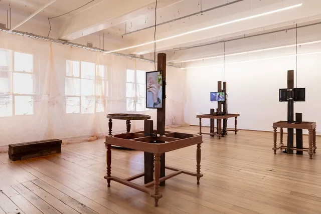 Videos displaying on wooden table and mosquito nets against the windows, at 'Inheritance' exhibition.