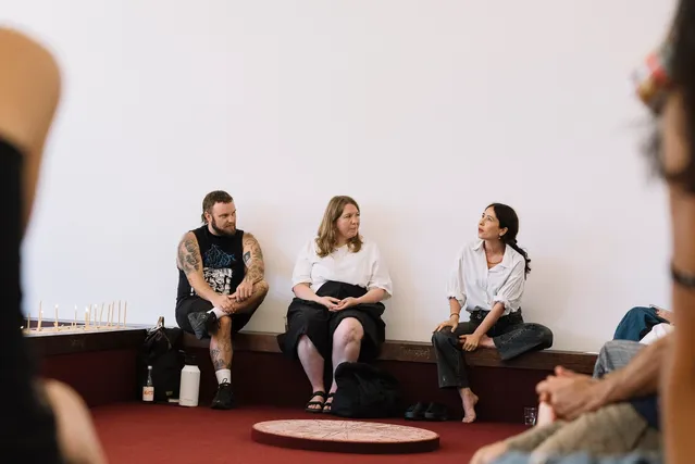Tina Stefanou and two audience members seated and having a conversation on a wooden bench.