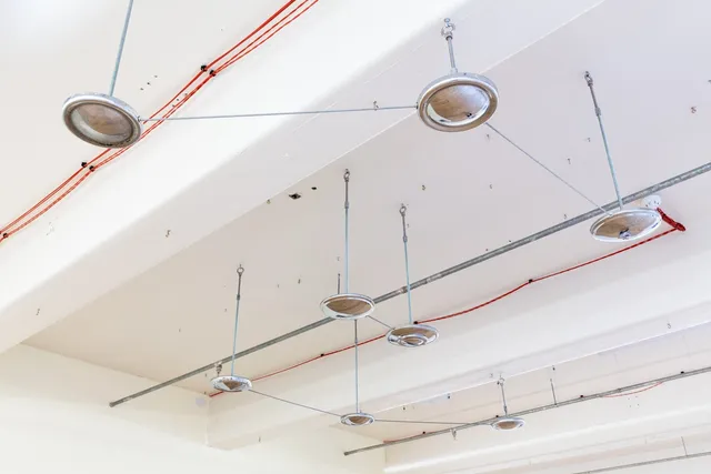 A collection of vintage hubcaps installed into the ceiling of West Space gallery. The hubcaps are arranged to mirror a constellation. There are also pipes and wires already in the ceiling.
