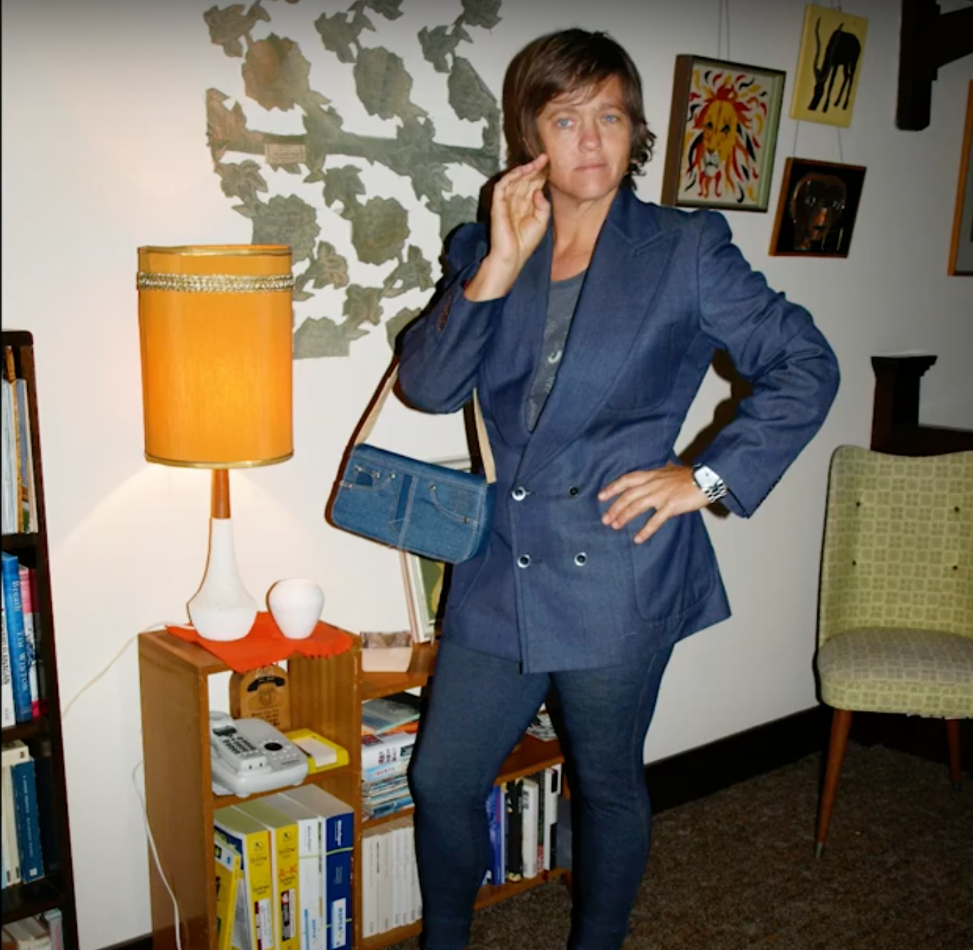 A person with a blue outfit standing in front of some furnitures and decors.