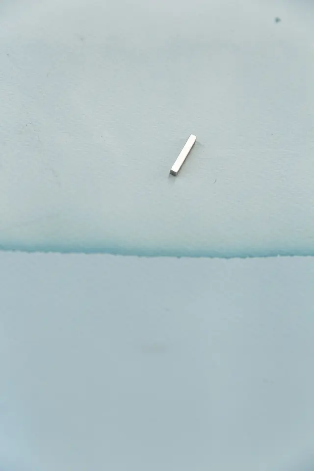 a piece of blotting paper died pale blue with organic dyes is held up by a magnet that is long and rectangular in shape