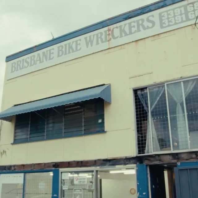 A cream and blue building with windows, doors, and the sign "BRISBANE BIKE WRECKERS".