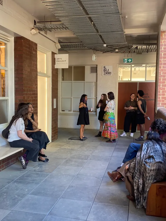 A group of people scattered through the balcony outside of West Space and Arts Project Australia.