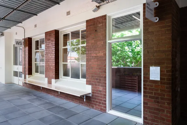 A brick space with tiled floor, glass windows, glass doors, a bench, and signs.