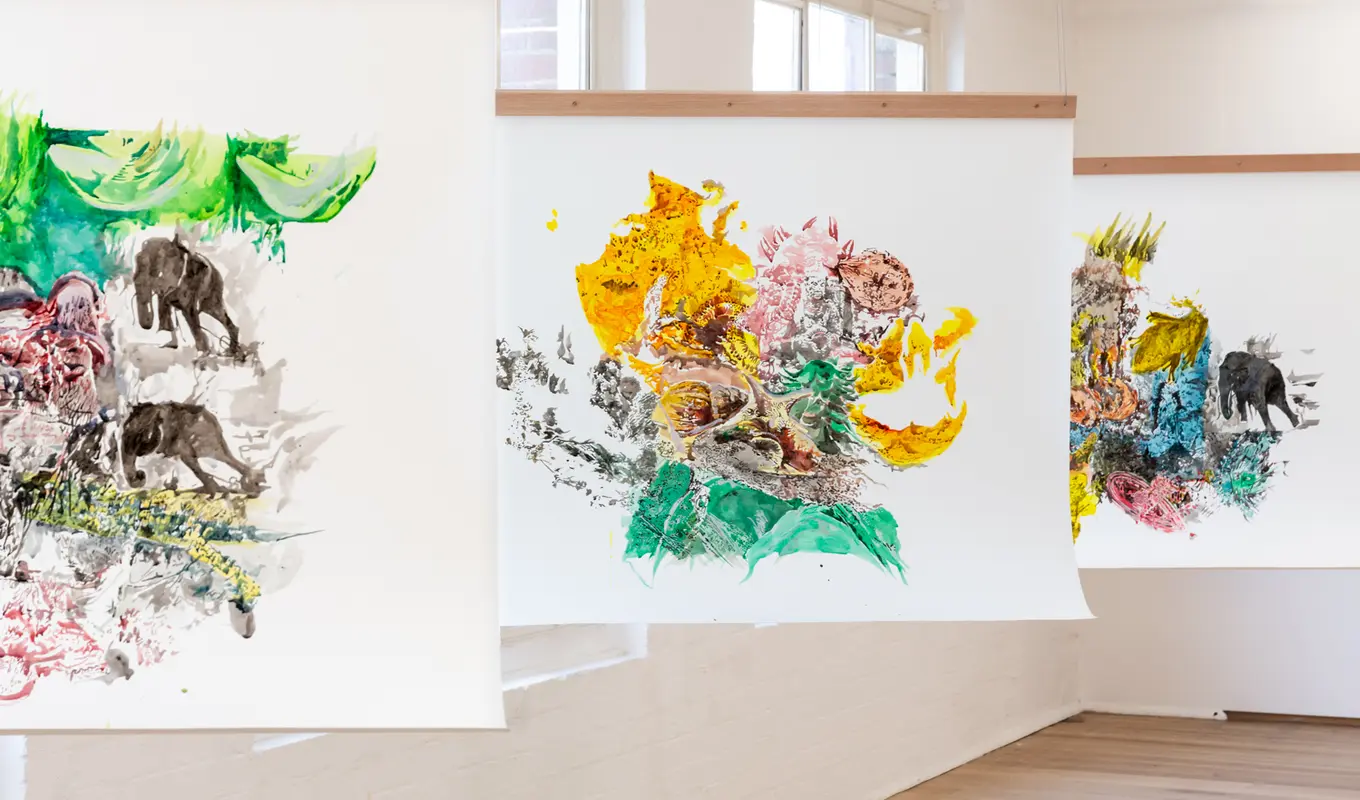 Three paintings hung in line from the ceiling.