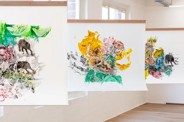 Three paintings hung in line from the ceiling.