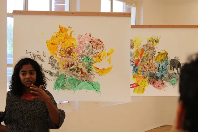 A person speaking in front of an artwork.