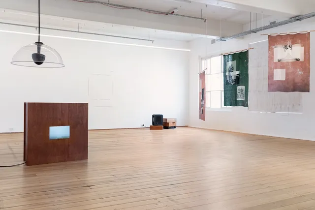 Install view of 'language to reach with' with Nithya Iyers textile works hanging to the right and Chi Trans work sitting on the floor to the left.