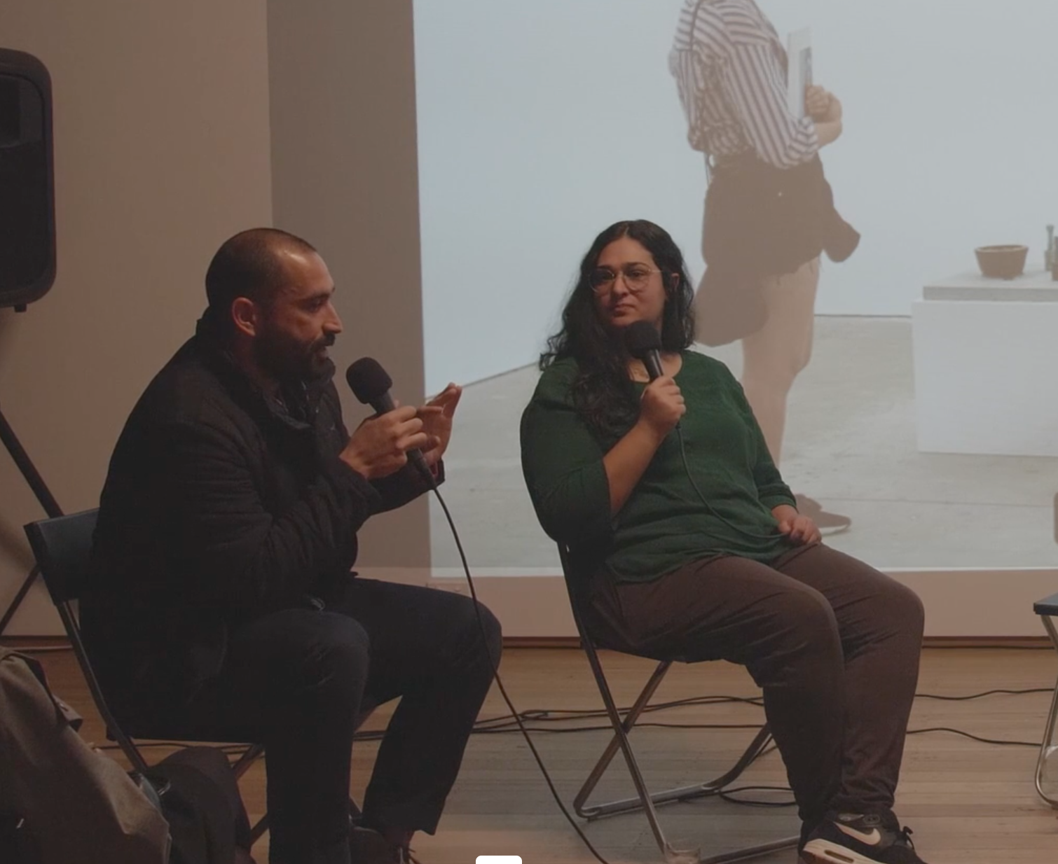 Two people sitting and speaking to the microphone.