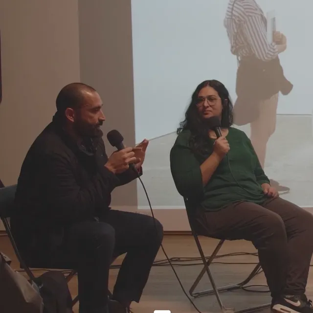 Two people sitting and speaking to the microphone.