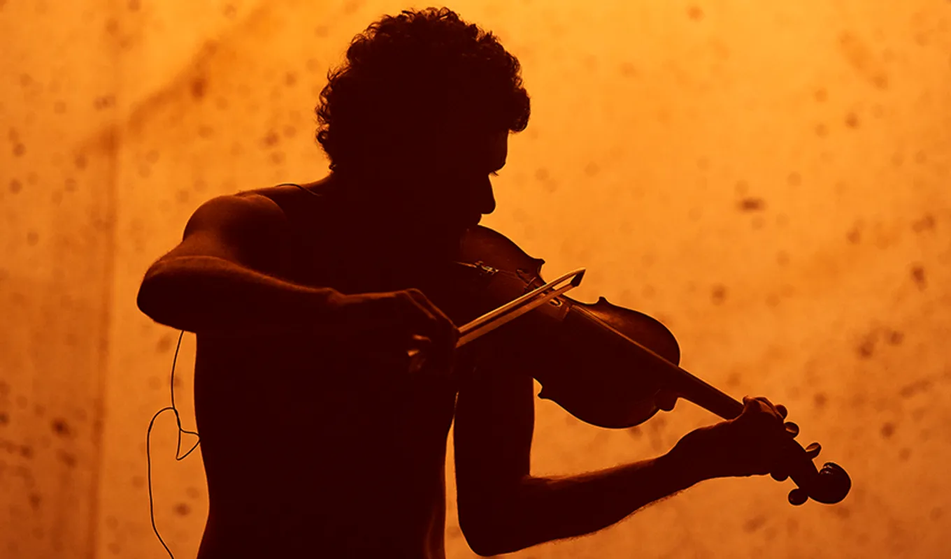 The silhouette of a person playing violin.