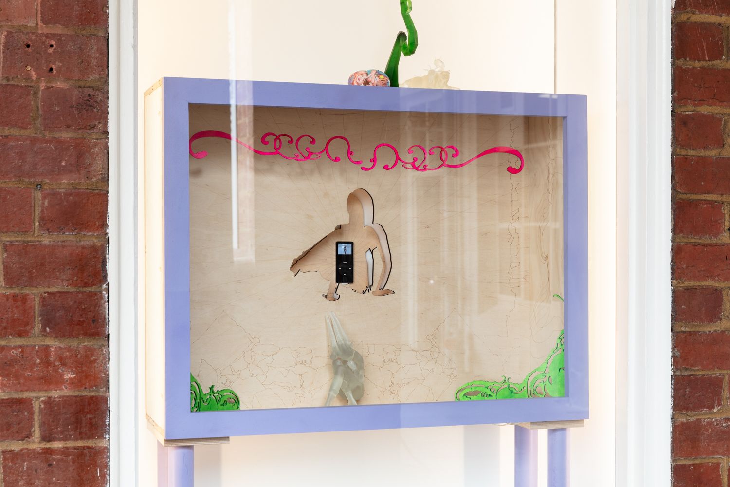 Installation view of the West Space window showing a wooden box containing a mixed media sculptural work.